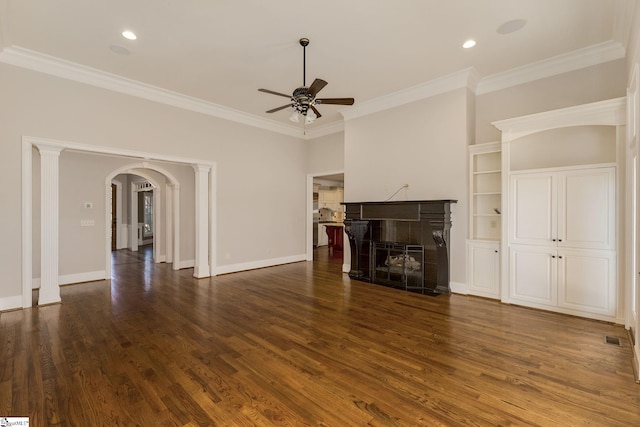 unfurnished living room featuring arched walkways, crown molding, dark wood finished floors, a fireplace, and baseboards