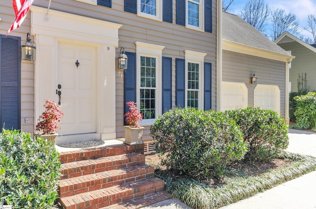 entrance to property with a shingled roof and an attached garage