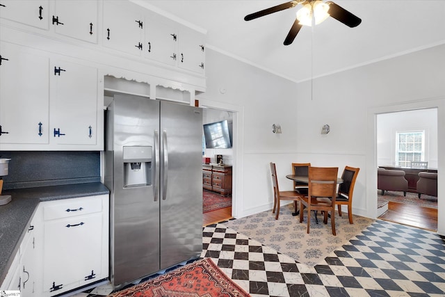 kitchen with a ceiling fan, white cabinetry, ornamental molding, stainless steel fridge with ice dispenser, and dark countertops