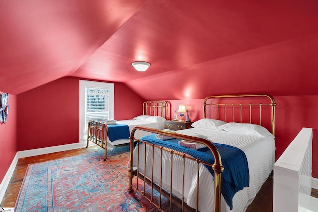 bedroom featuring vaulted ceiling, wood finished floors, and baseboards