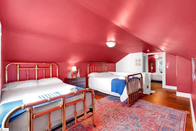 bedroom with lofted ceiling, dark wood-style flooring, and baseboards