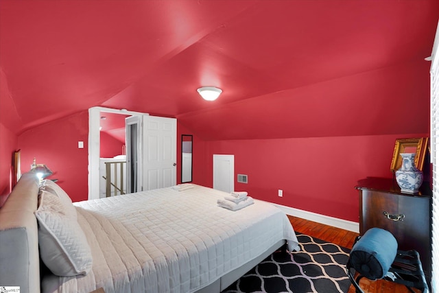 bedroom with lofted ceiling, wood finished floors, and baseboards