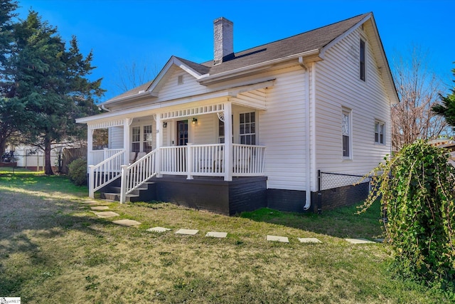 view of front of house featuring covered porch, a chimney, fence, and a front yard