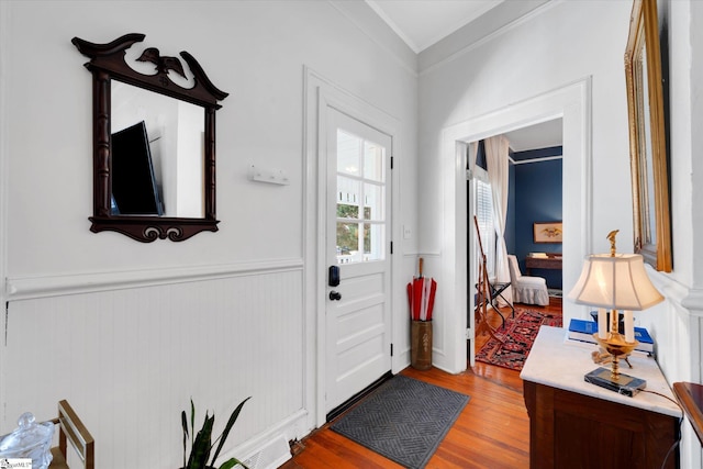 entryway featuring a wainscoted wall, ornamental molding, and wood finished floors