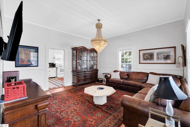 living room featuring a chandelier, ornamental molding, and wood finished floors