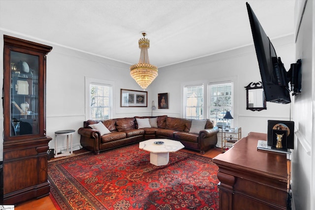 living area with ornamental molding, light wood-style flooring, and an inviting chandelier