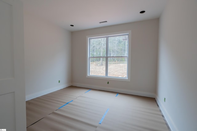 empty room with light wood-style flooring, visible vents, and baseboards