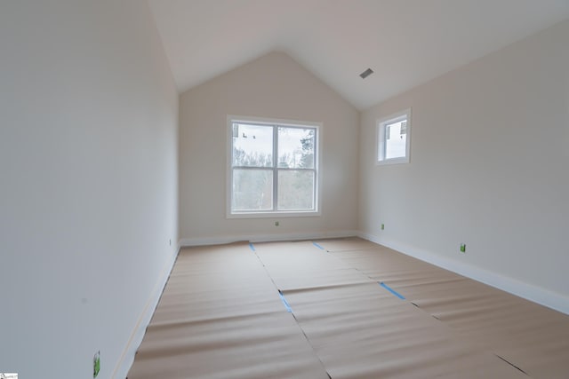 spare room with lofted ceiling, visible vents, and baseboards