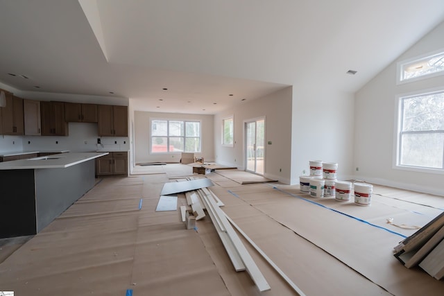 kitchen with visible vents, baseboards, lofted ceiling, open floor plan, and light countertops