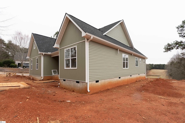 view of side of home featuring crawl space and a shingled roof