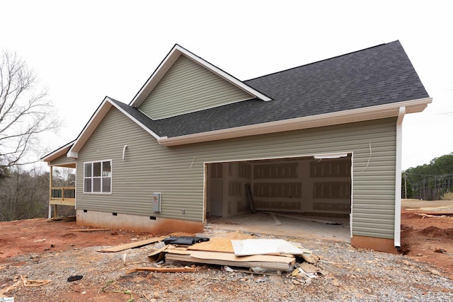 exterior space featuring crawl space, an attached garage, and roof with shingles