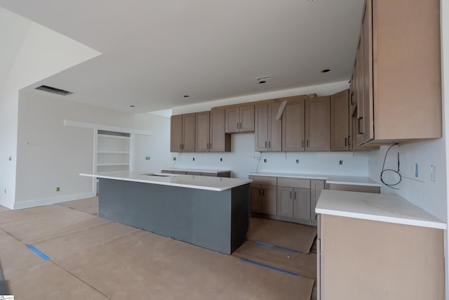 kitchen with light countertops, a center island, visible vents, and baseboards