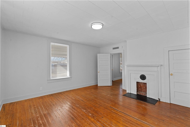 unfurnished living room with visible vents, a fireplace, baseboards, and hardwood / wood-style flooring