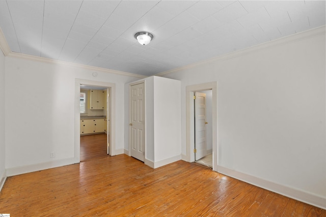 unfurnished bedroom featuring light wood-style floors, baseboards, and ornamental molding