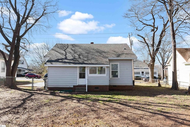 rear view of house with entry steps, crawl space, a fenced backyard, and roof with shingles