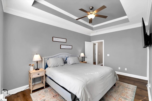 bedroom featuring ornamental molding, dark wood-type flooring, a raised ceiling, and baseboards