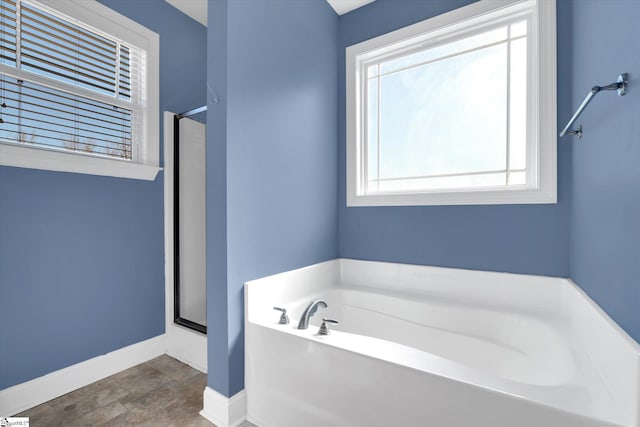 full bath with a garden tub, a shower stall, and baseboards