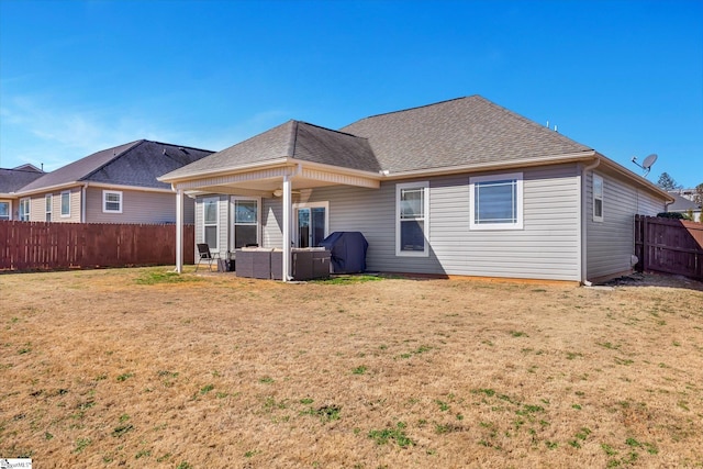 rear view of house with a fenced backyard, outdoor lounge area, a shingled roof, and a yard