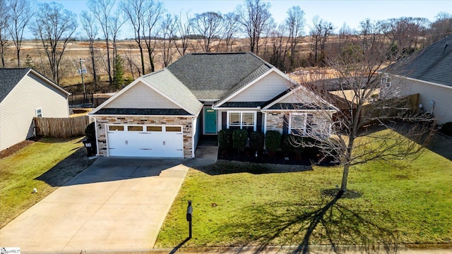 craftsman house with a front yard, fence, driveway, and an attached garage