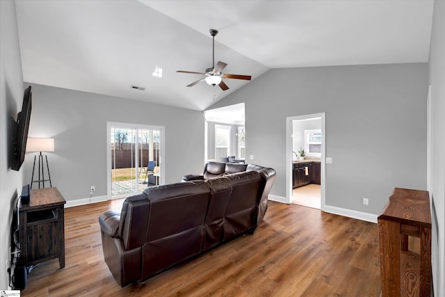 living room with baseboards, visible vents, a ceiling fan, lofted ceiling, and dark wood-style flooring