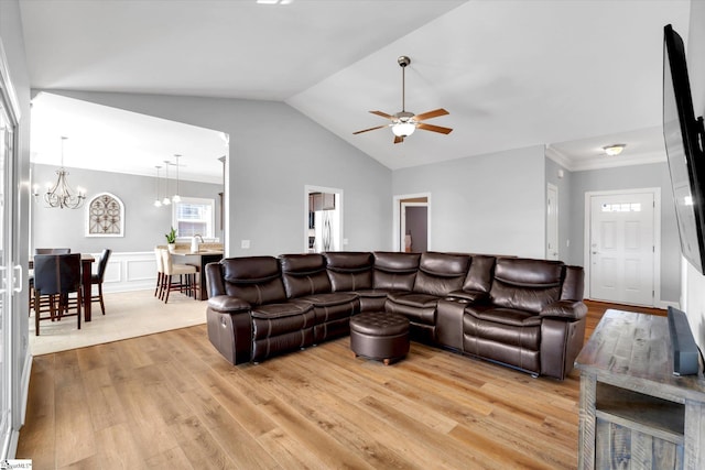 living area with lofted ceiling, ornamental molding, ceiling fan with notable chandelier, and wood finished floors