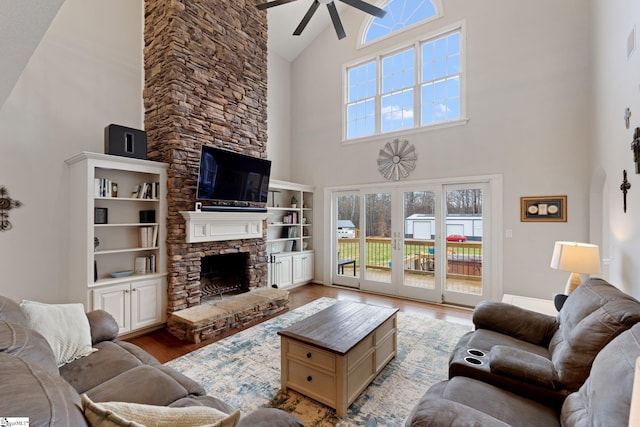 living area featuring visible vents, a ceiling fan, light wood-style floors, a fireplace, and high vaulted ceiling