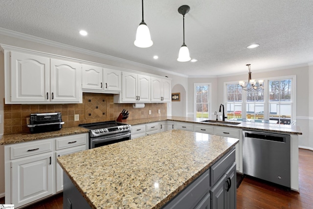 kitchen featuring stainless steel appliances, a peninsula, a sink, white cabinetry, and hanging light fixtures