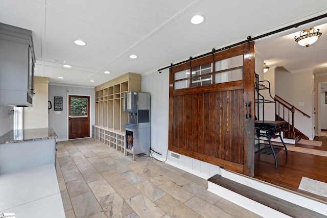 interior space with ornamental molding, a barn door, dark stone countertops, and recessed lighting