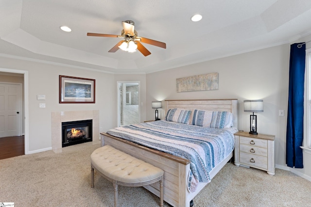 bedroom featuring crown molding, a fireplace, a raised ceiling, light carpet, and baseboards