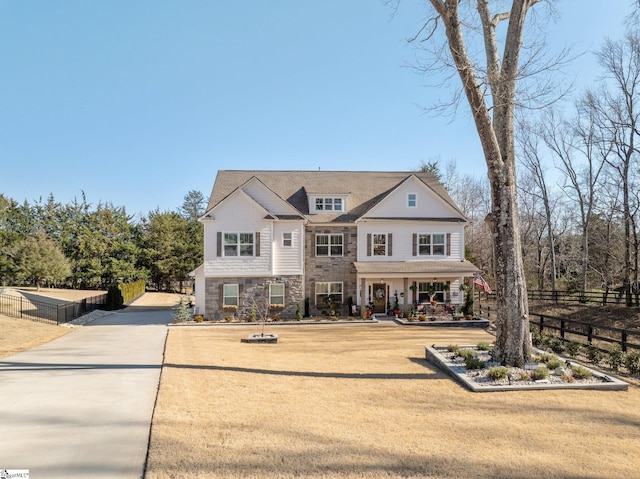 view of front facade with stone siding, fence, and a front lawn