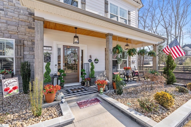 doorway to property featuring a porch and stone siding