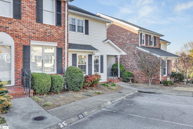 view of front of home featuring brick siding and a shingled roof