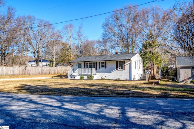 view of front of home featuring a front lawn, a chimney, fence, and brick siding