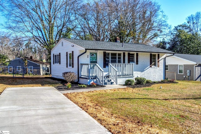 view of front of house with a porch, brick siding, fence, a chimney, and a front yard