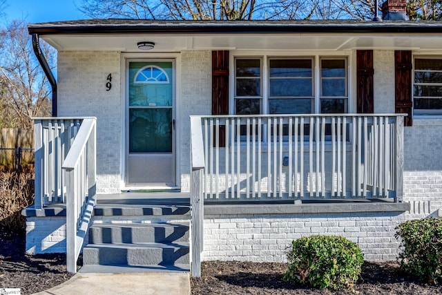 entrance to property featuring covered porch and brick siding