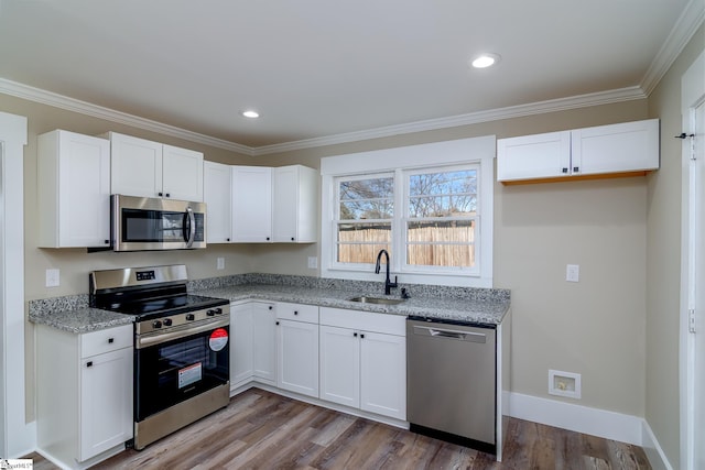 kitchen with light stone counters, appliances with stainless steel finishes, a sink, and white cabinetry