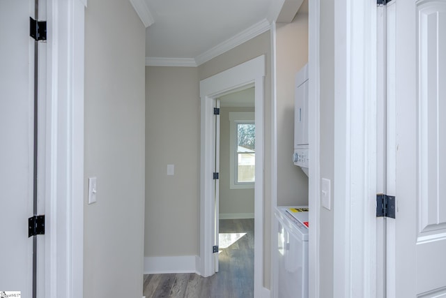 interior space with baseboards, stacked washer / dryer, light wood-style flooring, and crown molding