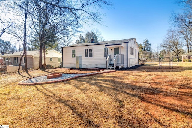 rear view of property with crawl space, fence, and a lawn