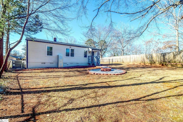 back of house with a fire pit, fence, crawl space, a lawn, and a chimney