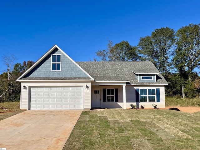 view of front of home featuring an attached garage, concrete driveway, a front lawn, and a shingled roof