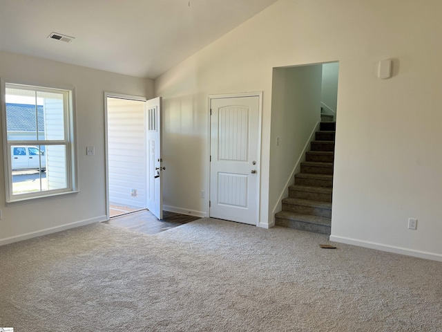 unfurnished room featuring baseboards, visible vents, stairway, vaulted ceiling, and carpet floors