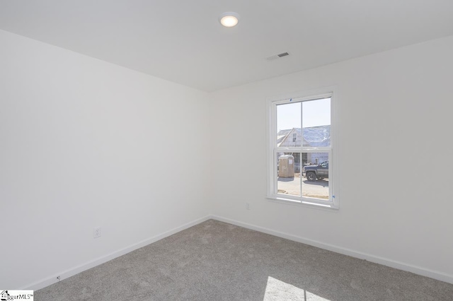 carpeted spare room featuring visible vents and baseboards