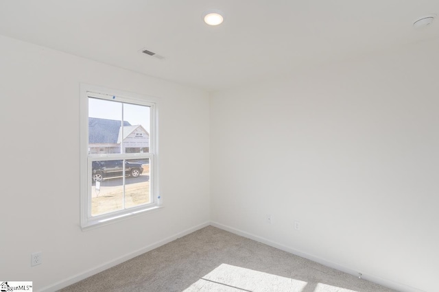 spare room with recessed lighting, light carpet, visible vents, and baseboards