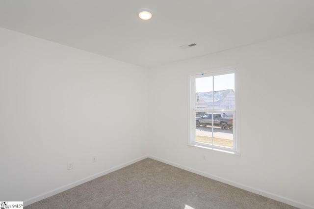 empty room with carpet flooring, visible vents, and baseboards