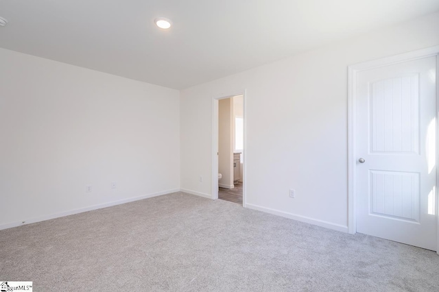 unfurnished room with baseboards, recessed lighting, and light colored carpet