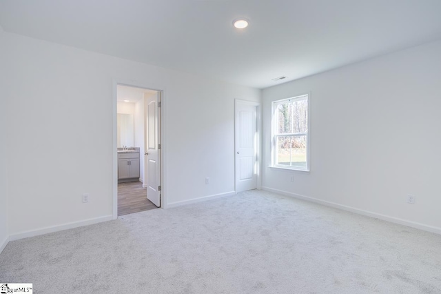 unfurnished bedroom featuring visible vents, baseboards, connected bathroom, and light colored carpet