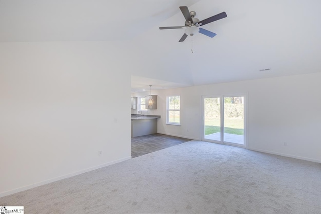 unfurnished living room with baseboards, visible vents, a ceiling fan, vaulted ceiling, and dark carpet