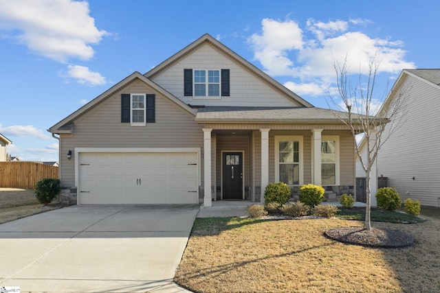 view of front of home with a porch, a garage, fence, driveway, and stone siding