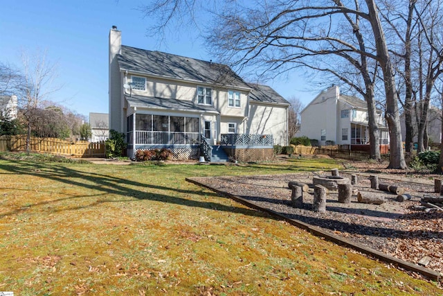 back of house featuring a yard, a chimney, fence, and a sunroom