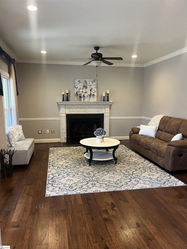 living area with a fireplace with flush hearth, dark wood-style flooring, ornamental molding, and baseboards